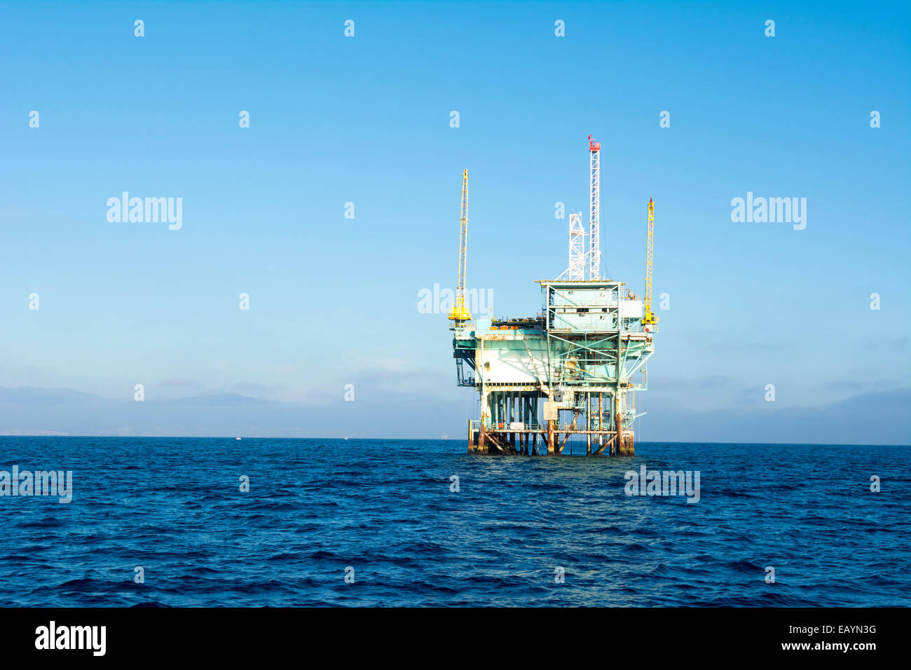 An offshore oil platform rests in deep ocean water on a clear, bright, sunny day. Stock Photo
