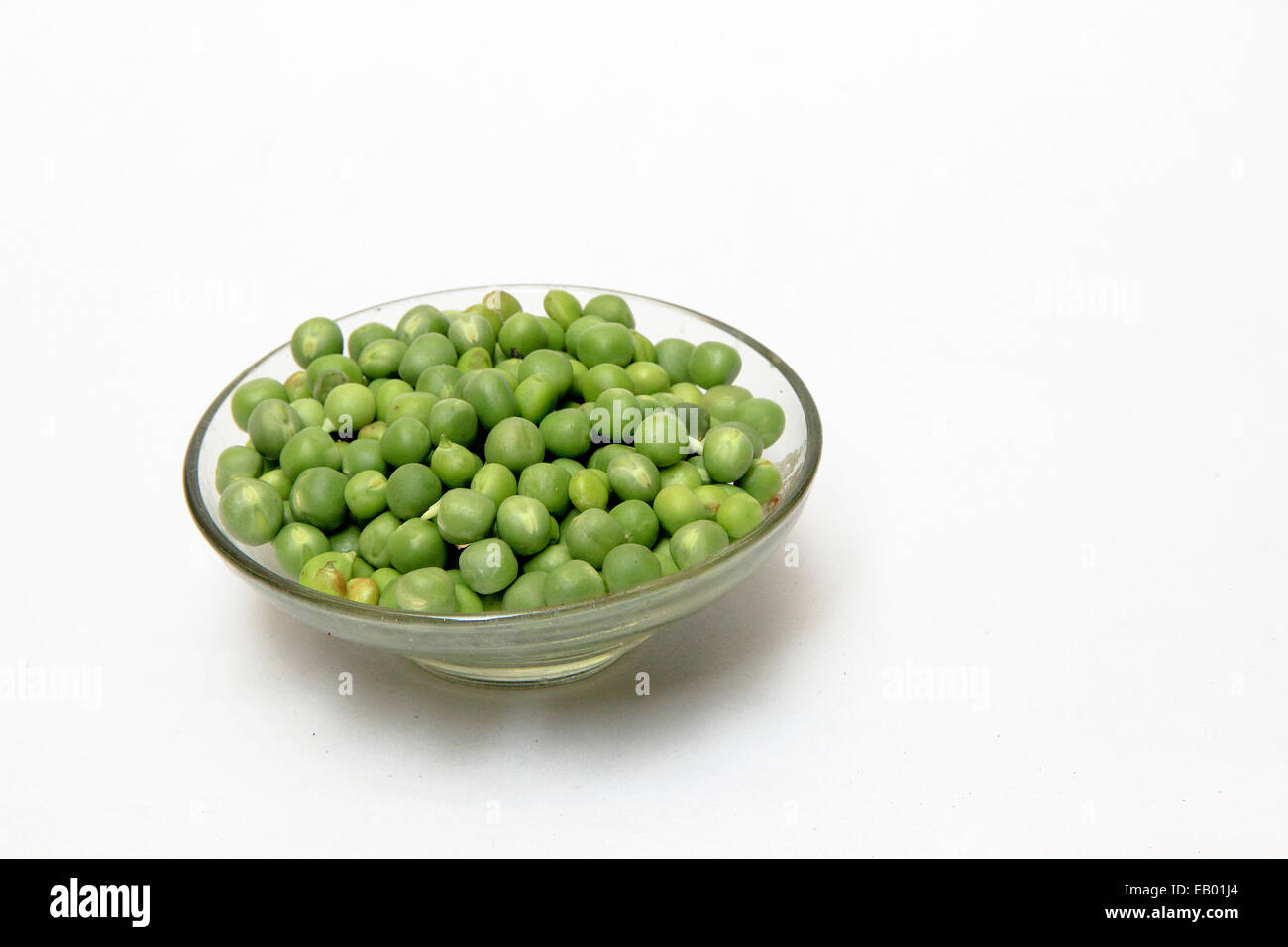 Glass dish containing fresh green peas, isolated on white Stock Photo