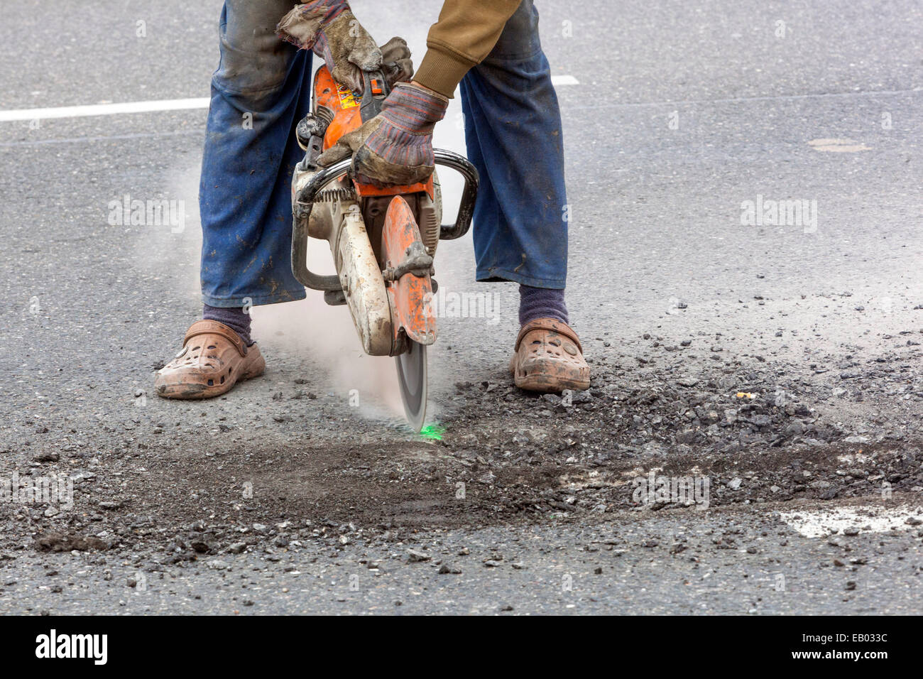 A man works cut asphalt road with a diamond cutter, No protective work gear, Czech Republic Stock Photo