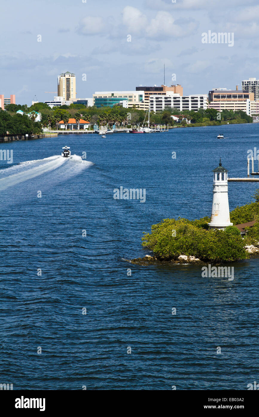 Miniature lighthouse on Davis Island, Tampa, Florida with boat and wake on the water and cityscape in the background. Stock Photo
