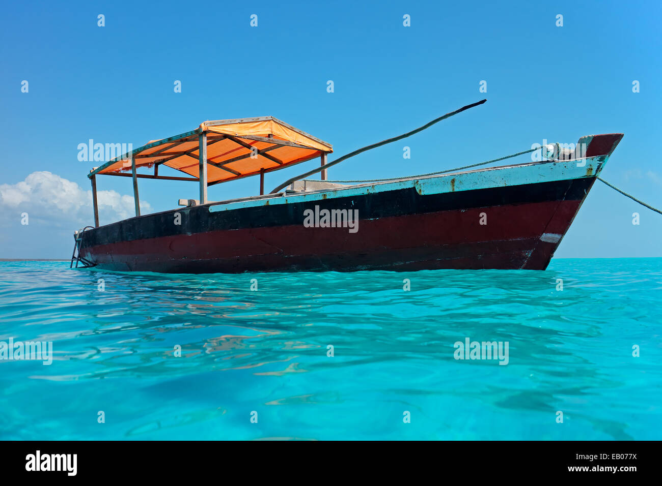 Wooden boat floating on the clear turquoise water of Zanzibar island ...