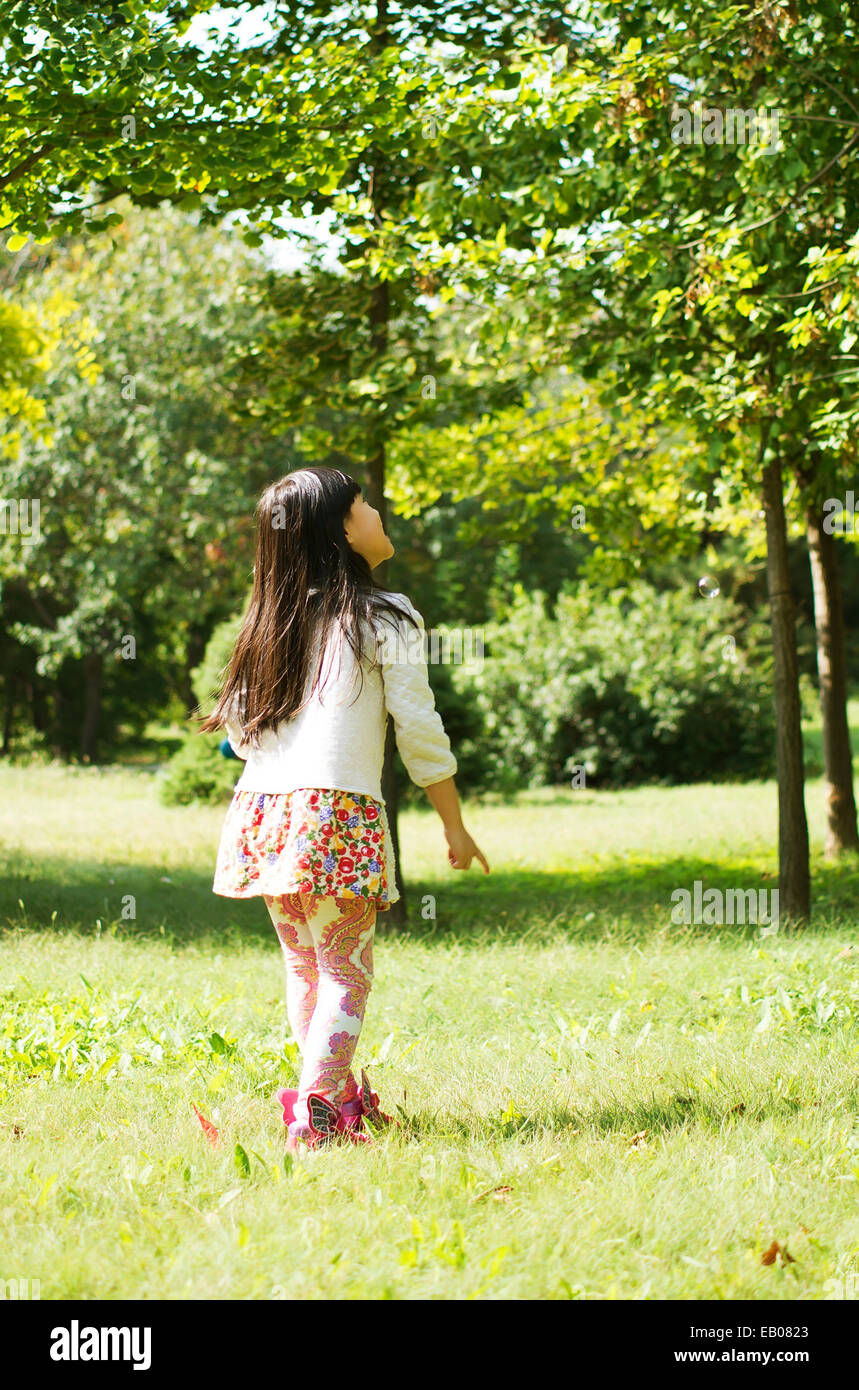 The little girl looked up at the leaves on the trees Stock Photo