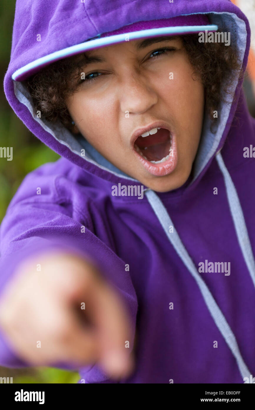 Young African American girl female child wearing hoody hoodie & baseball cap shouting and pointing to camera Stock Photo