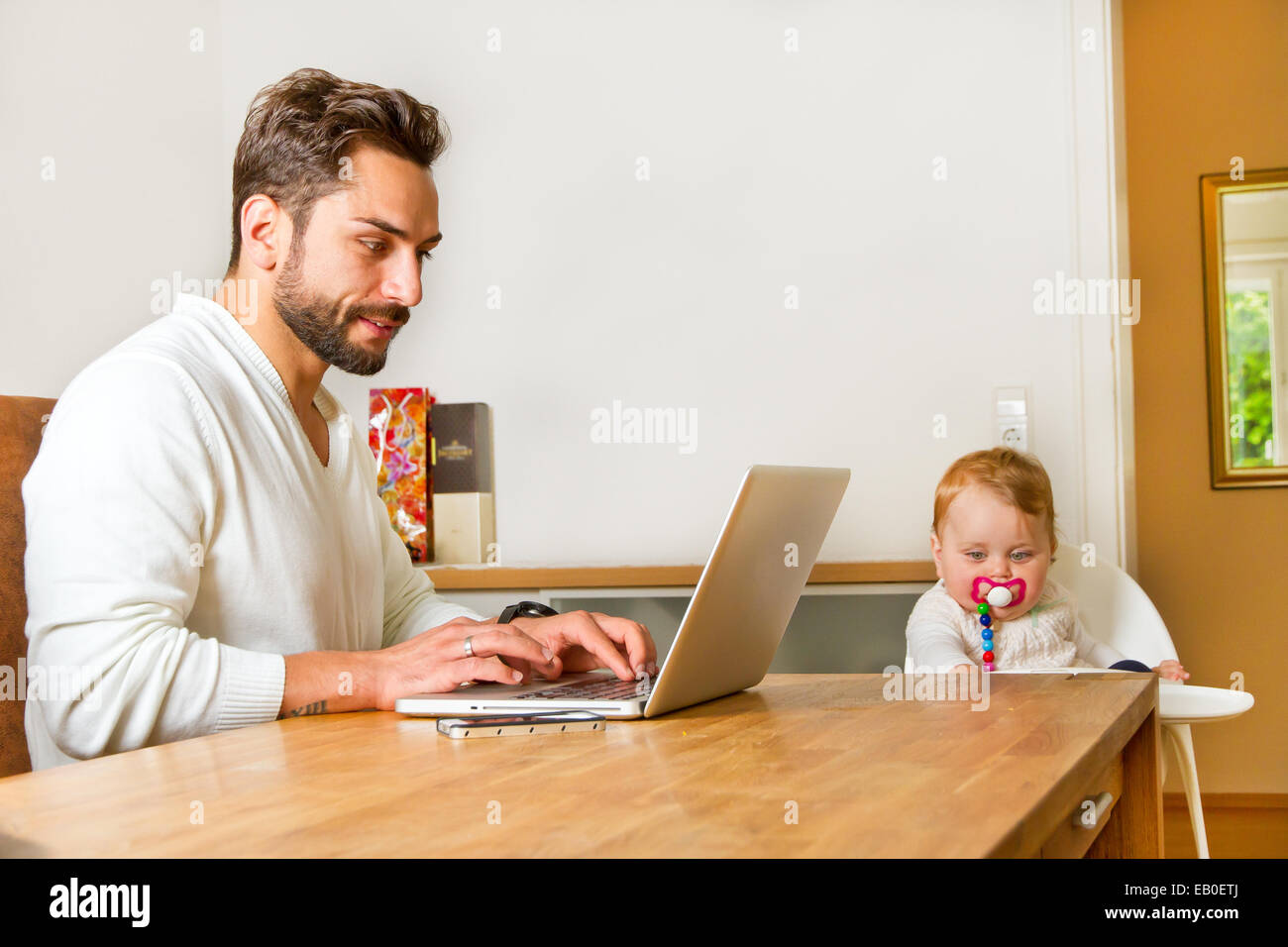 Father with baby works on laptop Stock Photo - Alamy