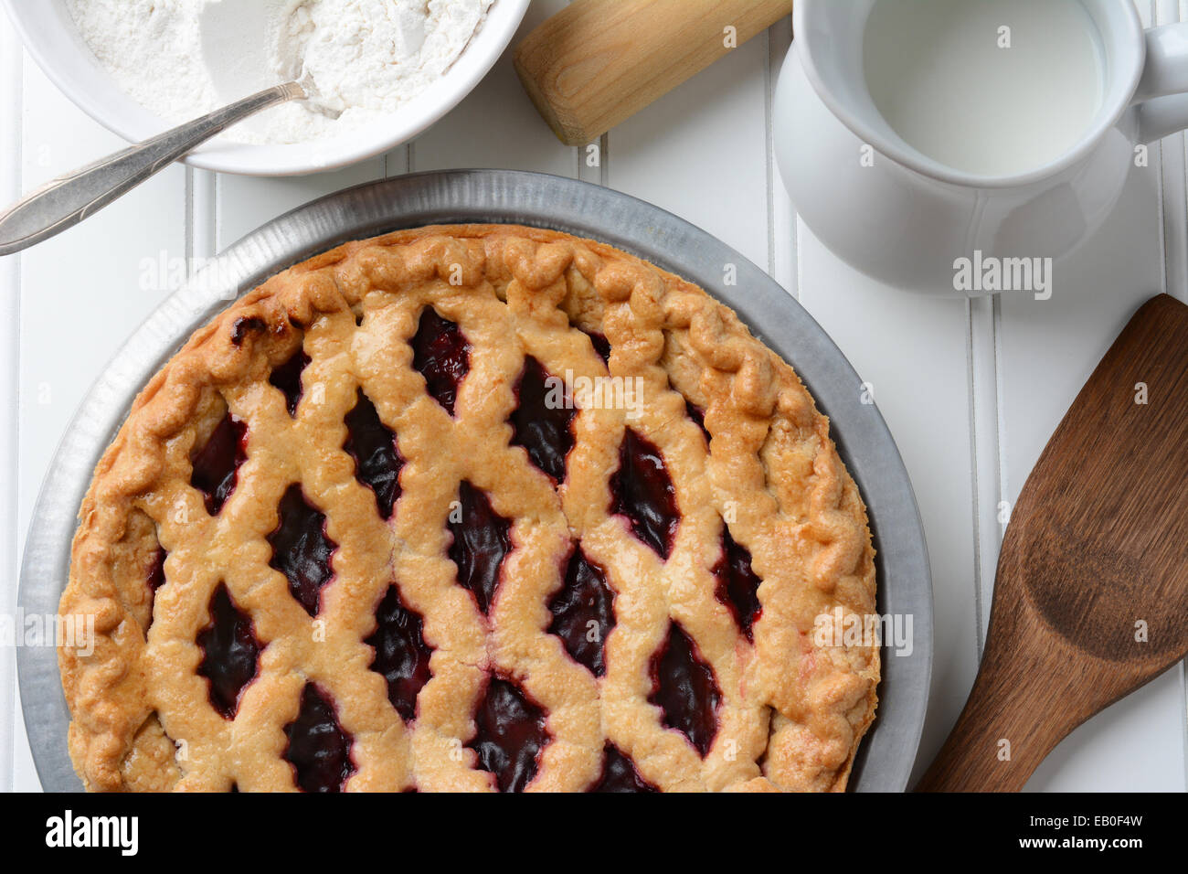 High angle shot of a fresh baked fruit pie with a lattice crust. the pie is surrounded by baking items. Horizontal format. Stock Photo