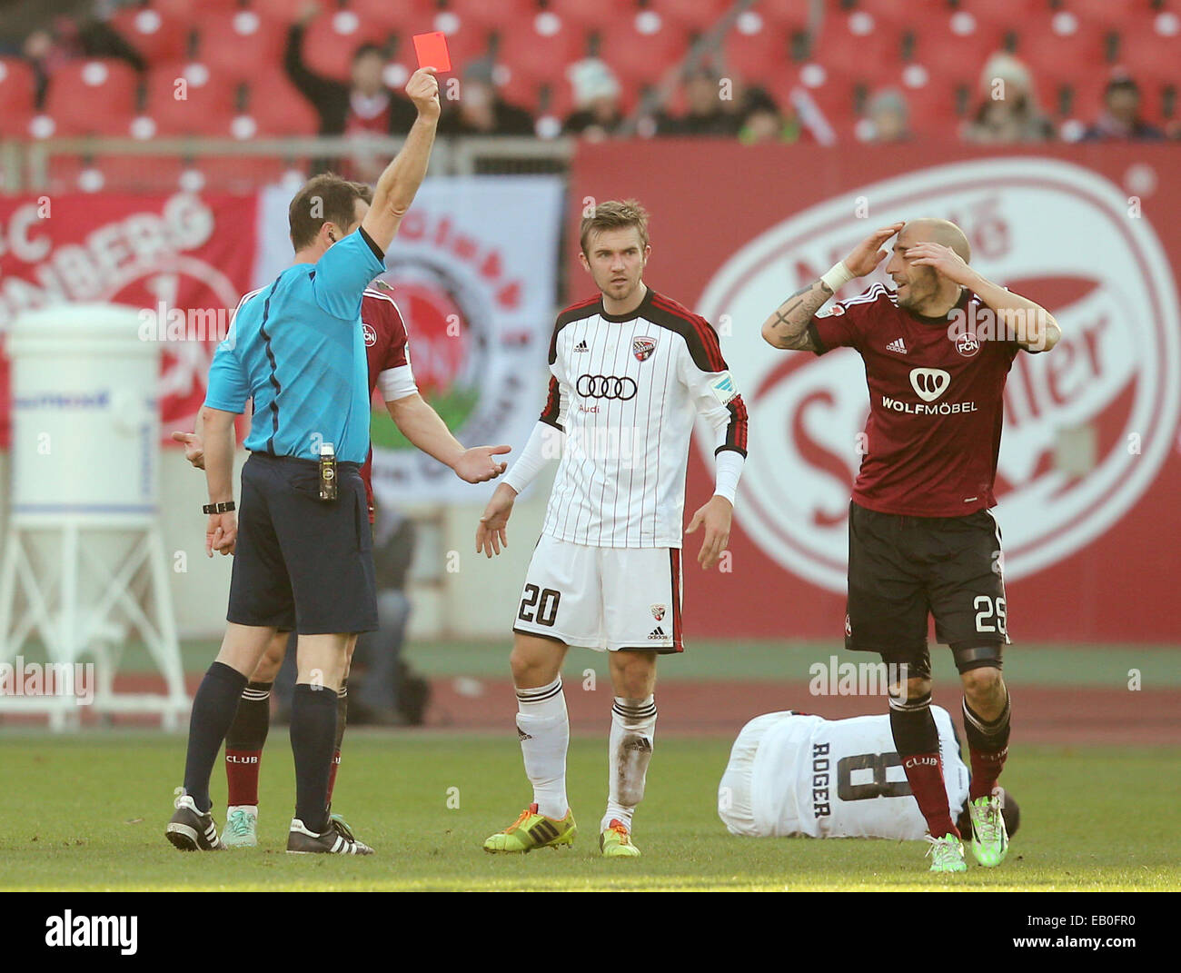Nuremberg, Germany. 23rd Nov, 2014. Referee Peter Sippel (L) gives a red card to Nuernberg's Javier Pinola (R) while Ingolstadt's Konstantin Engel (C) looks on during the German Bundesliga soccer match between 1. FC Nuernberg and FC Ingolstadt at the Grundig Stadium in Nuremberg, Germany, 23 November 2014. Photo: DANIEL KARMANN/dpa (EMBARGO CONDITIONS - ATTENTION - Due to the accreditation guidelines, the DFL only permits the publication and utilisation of up to 15 pictures per match on the internet and in online media during the match)/dpa/Alamy Live News Stock Photo