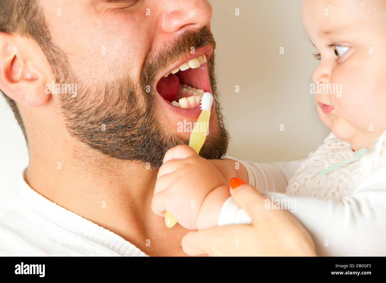 Baby brushing teeth of father Stock Photo