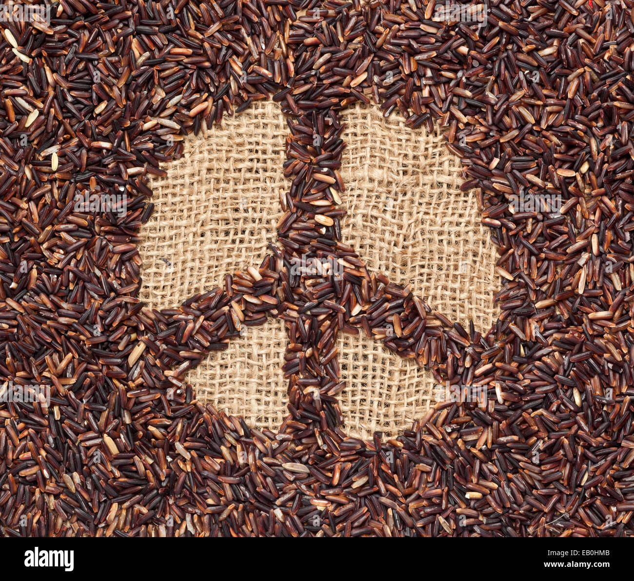 Red rice forming a peace symbol on burlap fabric Stock Photo