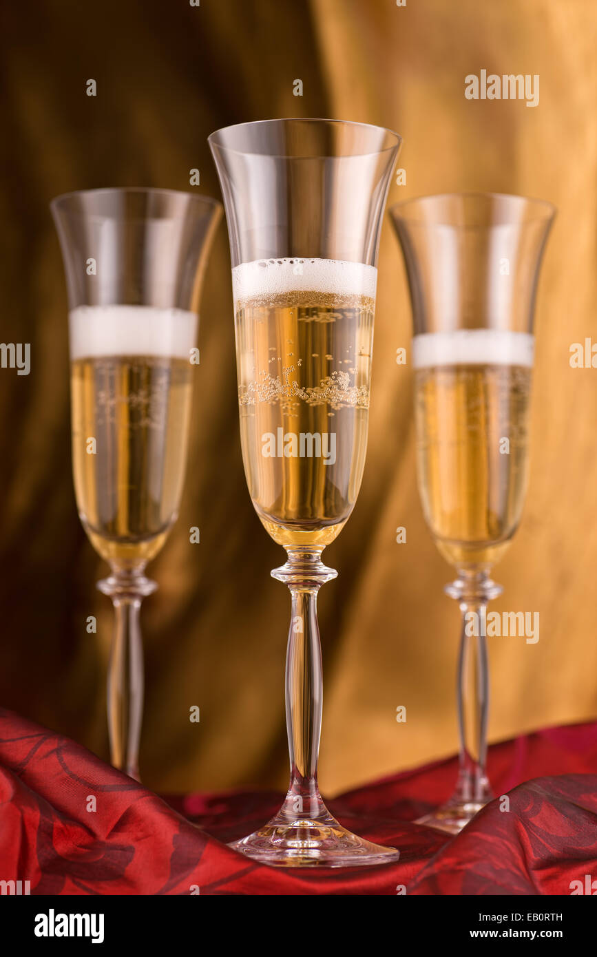 Champagne flutes against an abstract gold background. Stock Photo