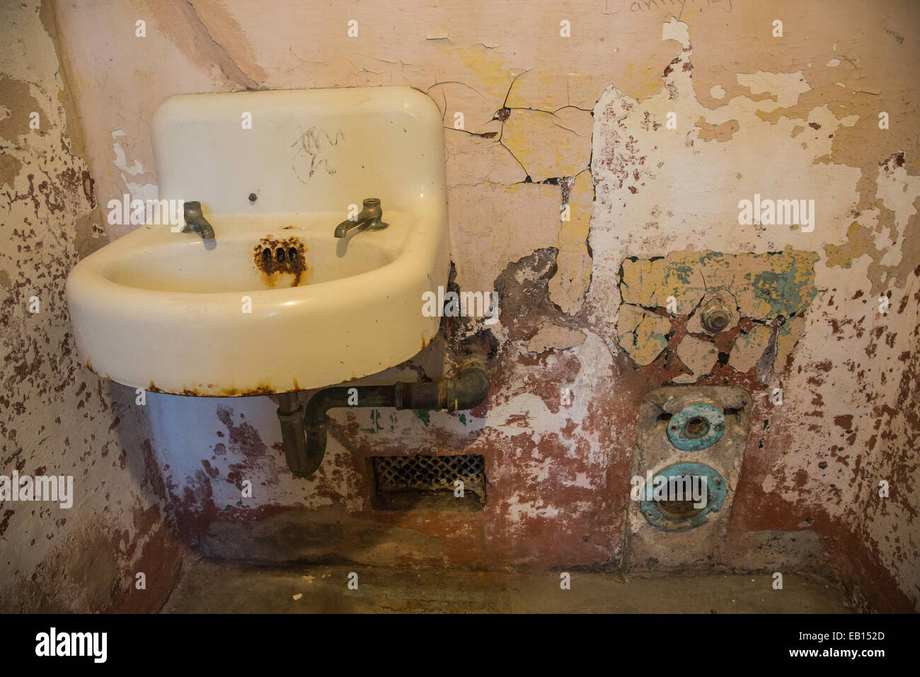 An old rusty sink, cracked walls and plumbing in an Alcratraz prison cell as part of the @Large: Ai Weiwei exhibit. Stock Photo