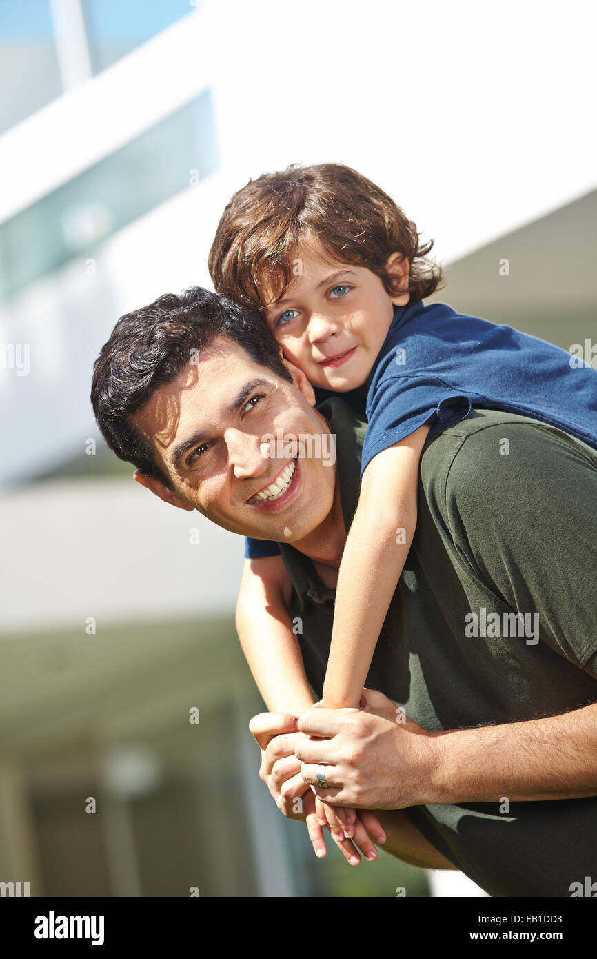 Happy father giving his smiling son a piggyback ride outside Stock Photo