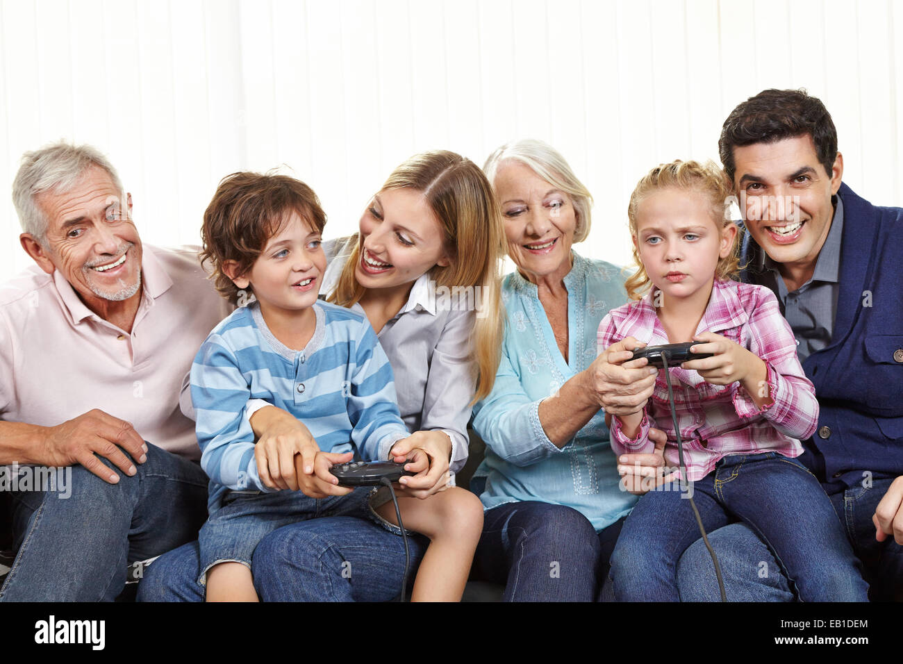 Happy family with controller playing video games on Smart TV in living room Stock Photo