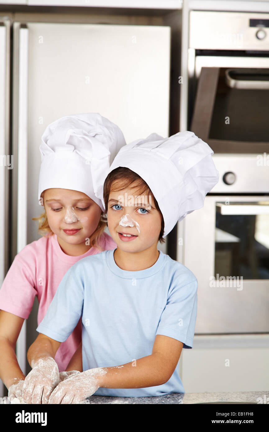Two children baking christmas cookies together in kitchen Stock Photo
