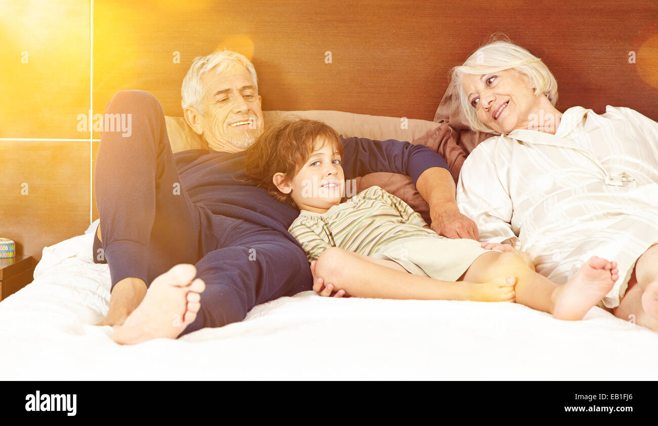 Happy grandparents with grandson laying on bed in a bedroom Stock Photo