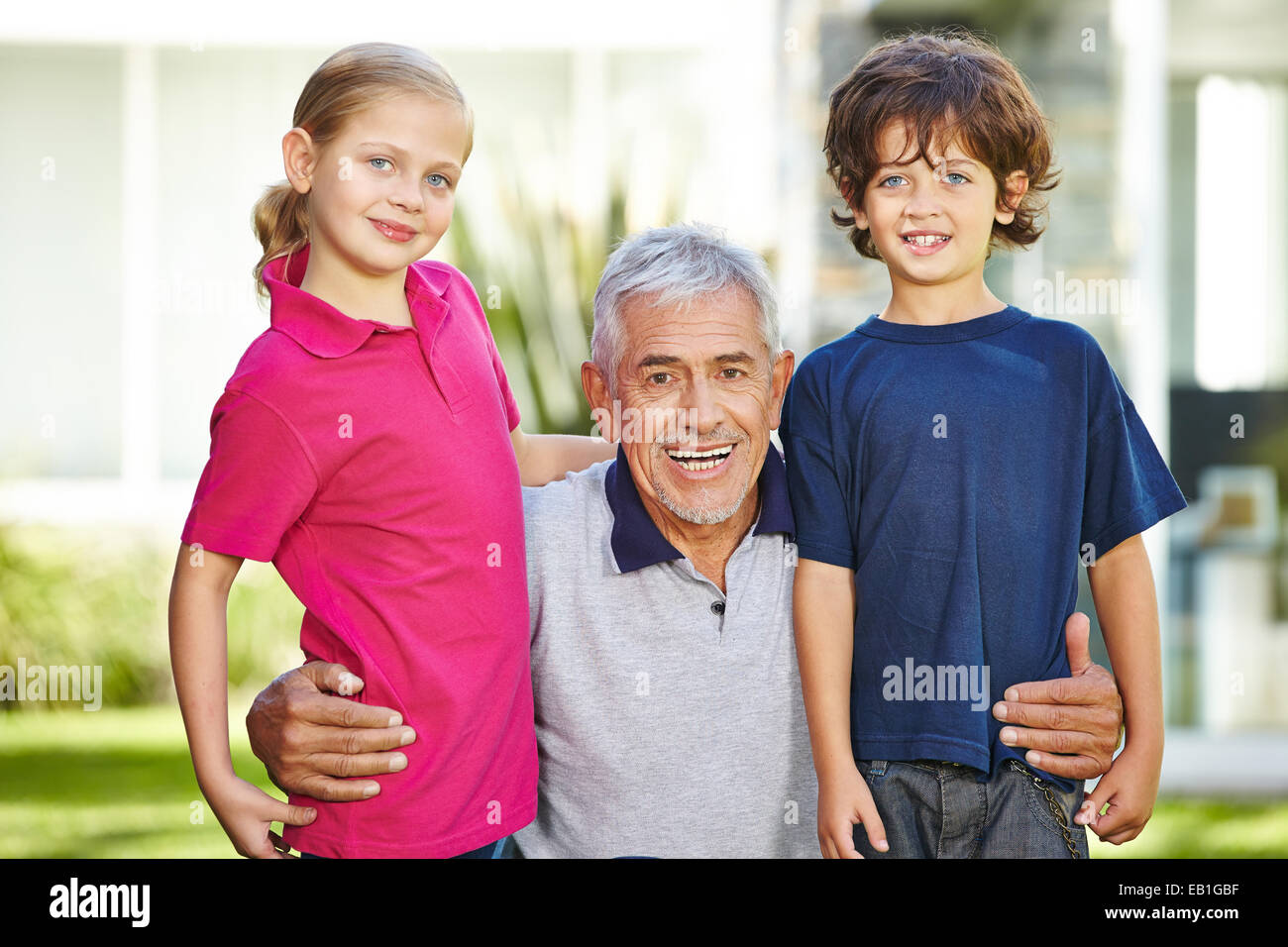 Portrait of smiling grandfather and two grandchildren in a garden Stock Photo