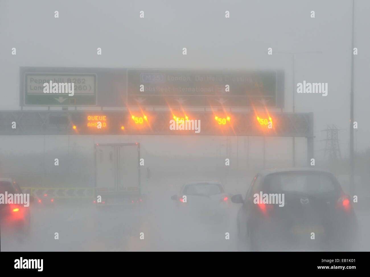 Speed limits and Queue warning signs light up during pouring rain over ...