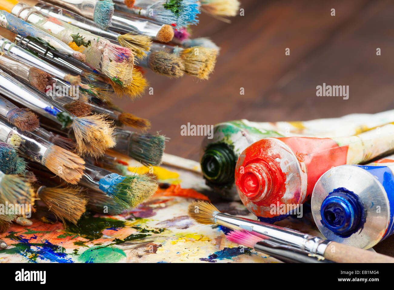 art brushes, oil paint tubes, artist palette on wooden table Stock Photo
