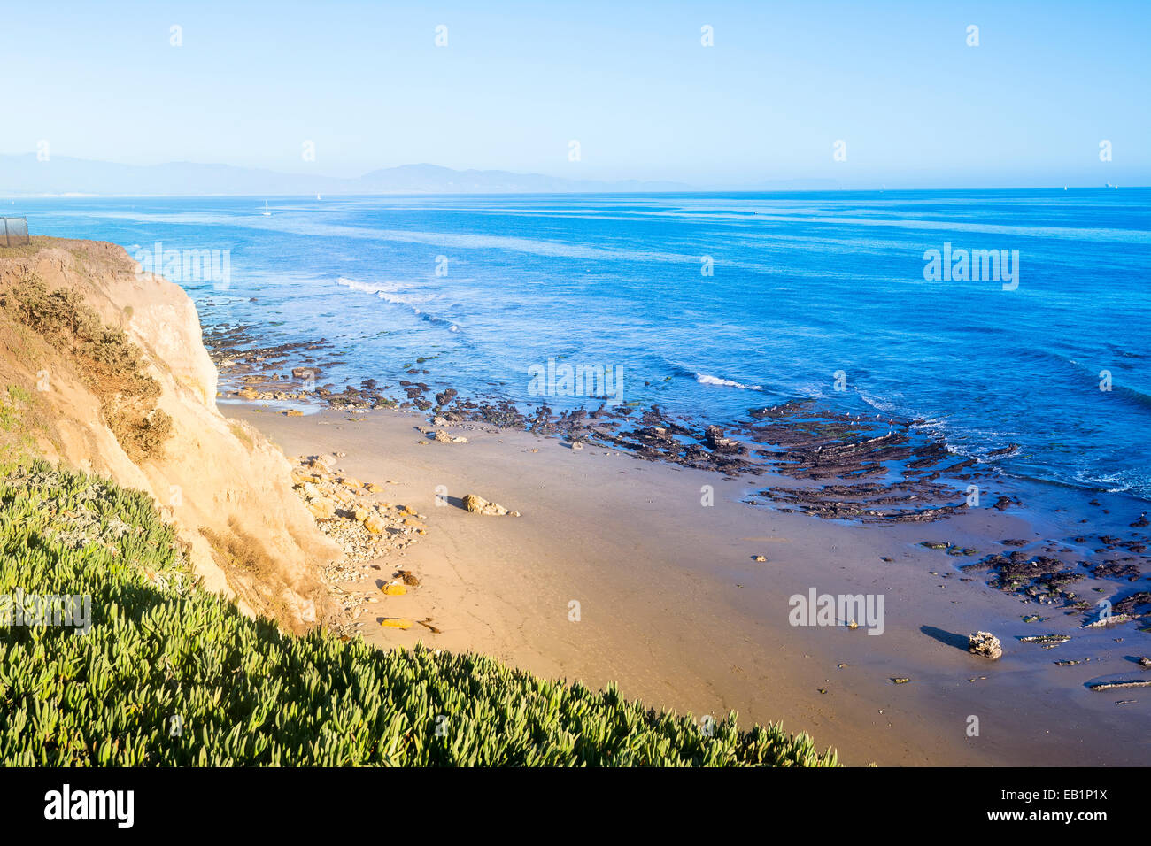 As the sun sets it lights up the side of a cliff in a rich, yellow tone as viewed from the edge of a cliff. Stock Photo