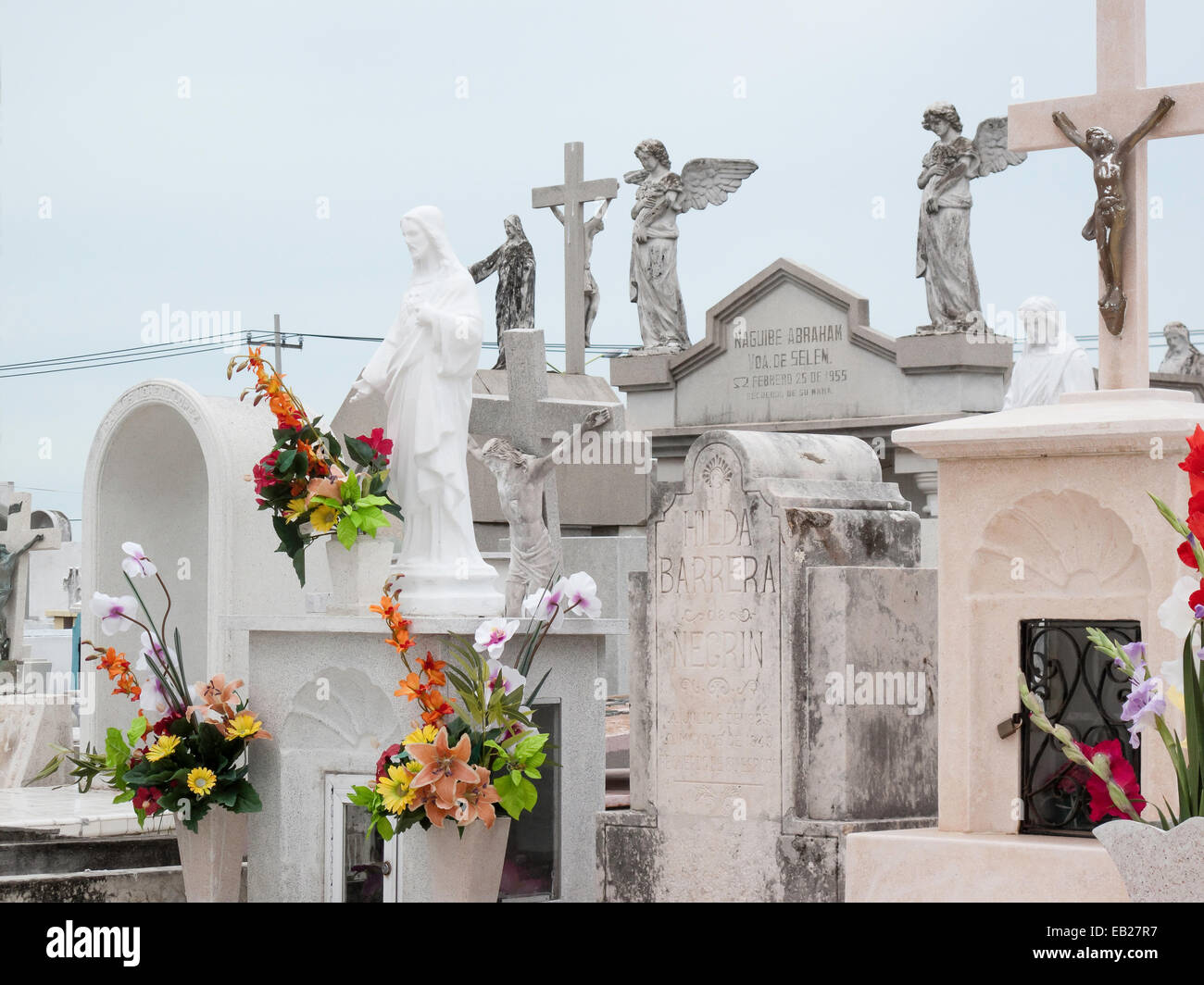 Panteon de San Roman cemetery detail of  marble headstones with carved crosses and angels adorned with colorful fresh flowers, Campeche, Mexico. Stock Photo