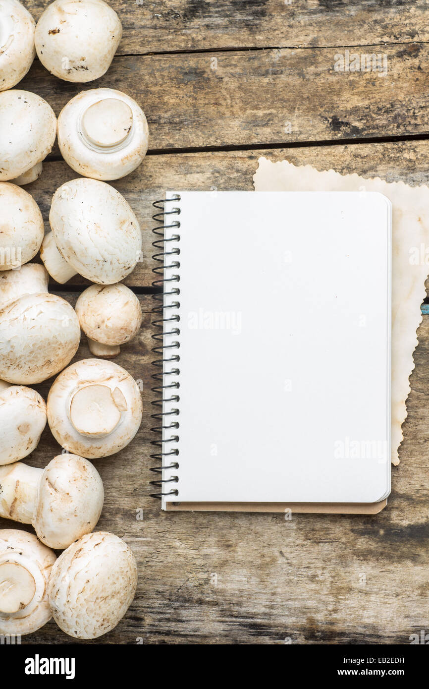 Mushrooms with blank cooking book or recipe sheet on wood background Stock Photo