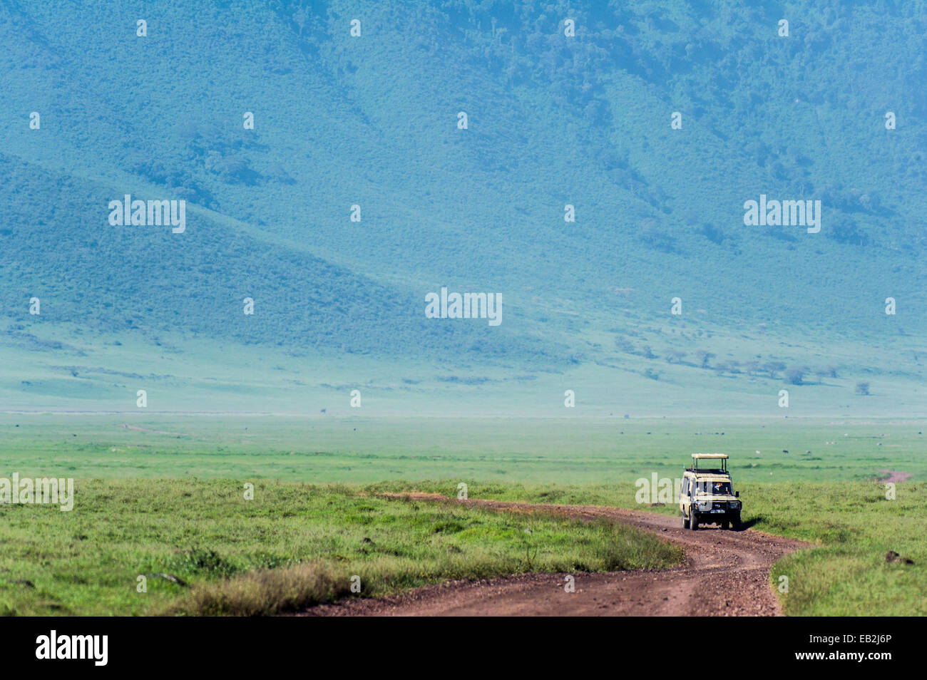 A safari vehicle crosses the savannah plain on the floor of a volcano caldera. Stock Photo