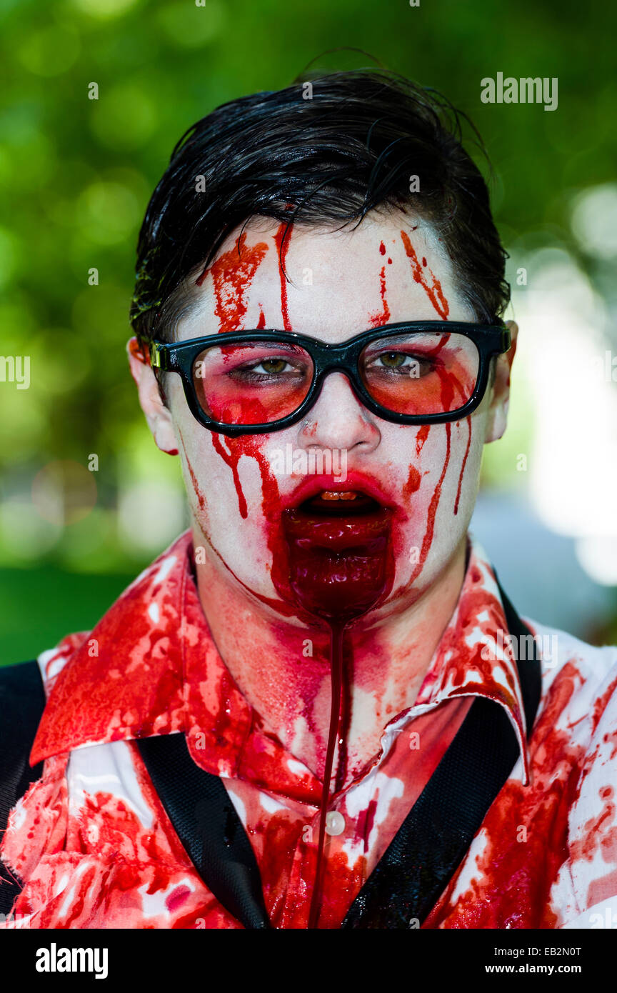 A drooling, blood-soaked zombie wearing glasses at a festival. Stock Photo