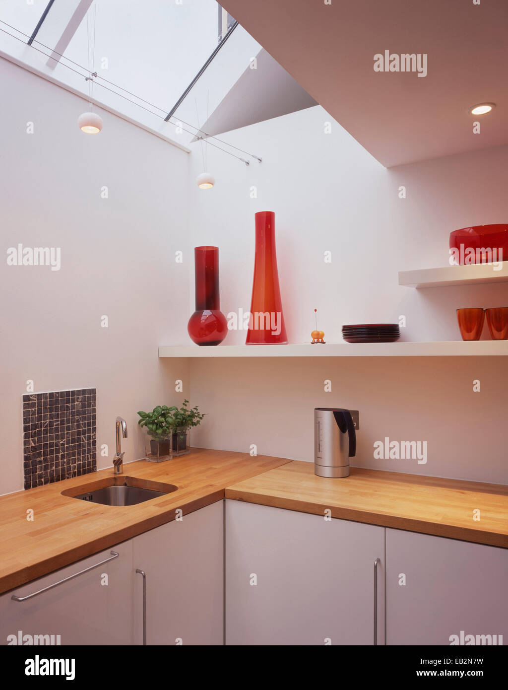Red glassware on kitchen shelving under skylight in converted