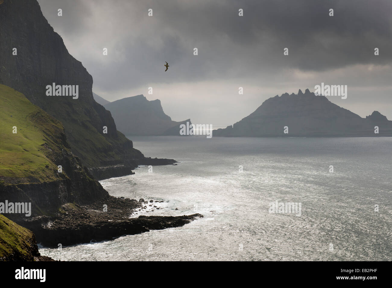 Cliffs in front of the silhouette of the rugged rocks of Tindhólmur, Vágar, Faroe Islands, Denmark Stock Photo