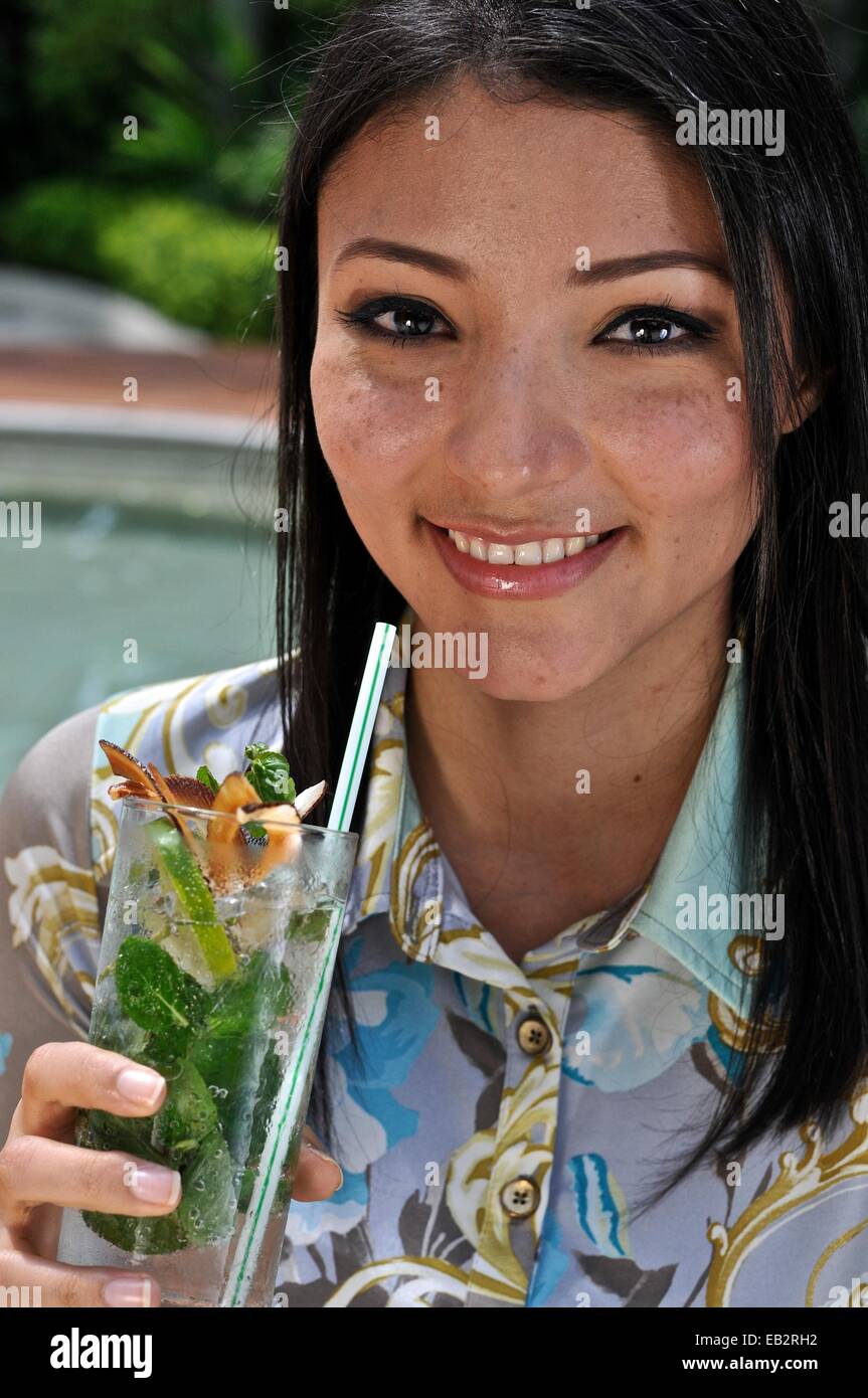 A young Latin American woman drinking a mojito at a hotel pool. Stock Photo