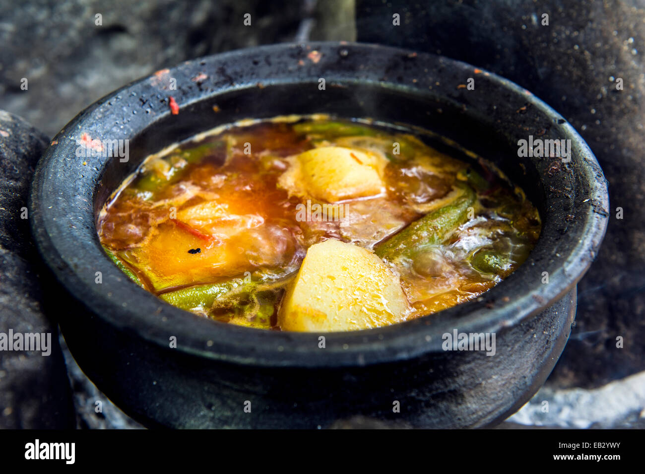 Traditional African food of potatoes, chilli and vegetables cooking in a handmade clay pot on a fire. Stock Photo