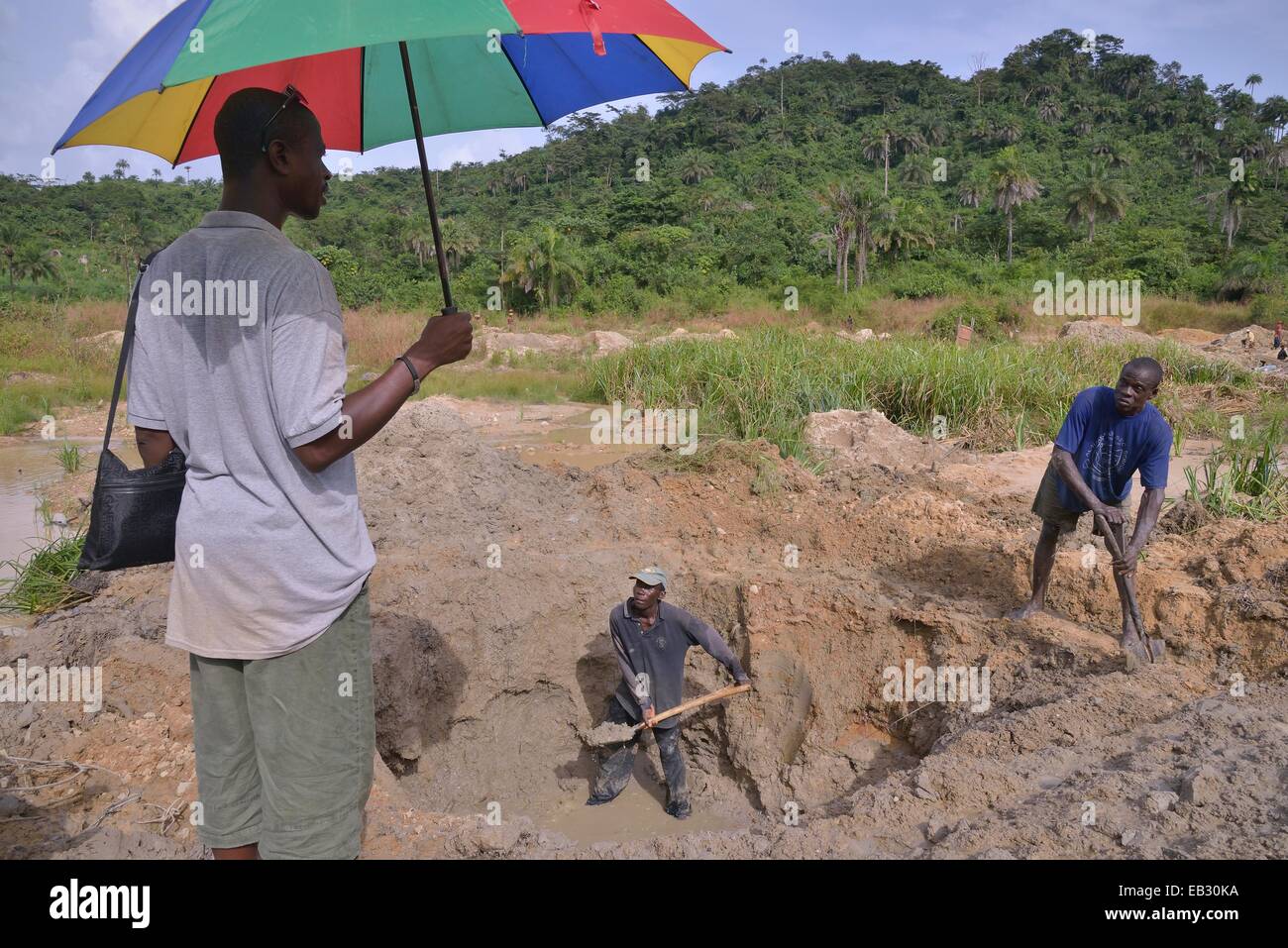 Diamond hunters digging a pit with shovels, supervisor holding a parasol, left, near Koidu, Koidu-Sefadu, Kono District Stock Photo