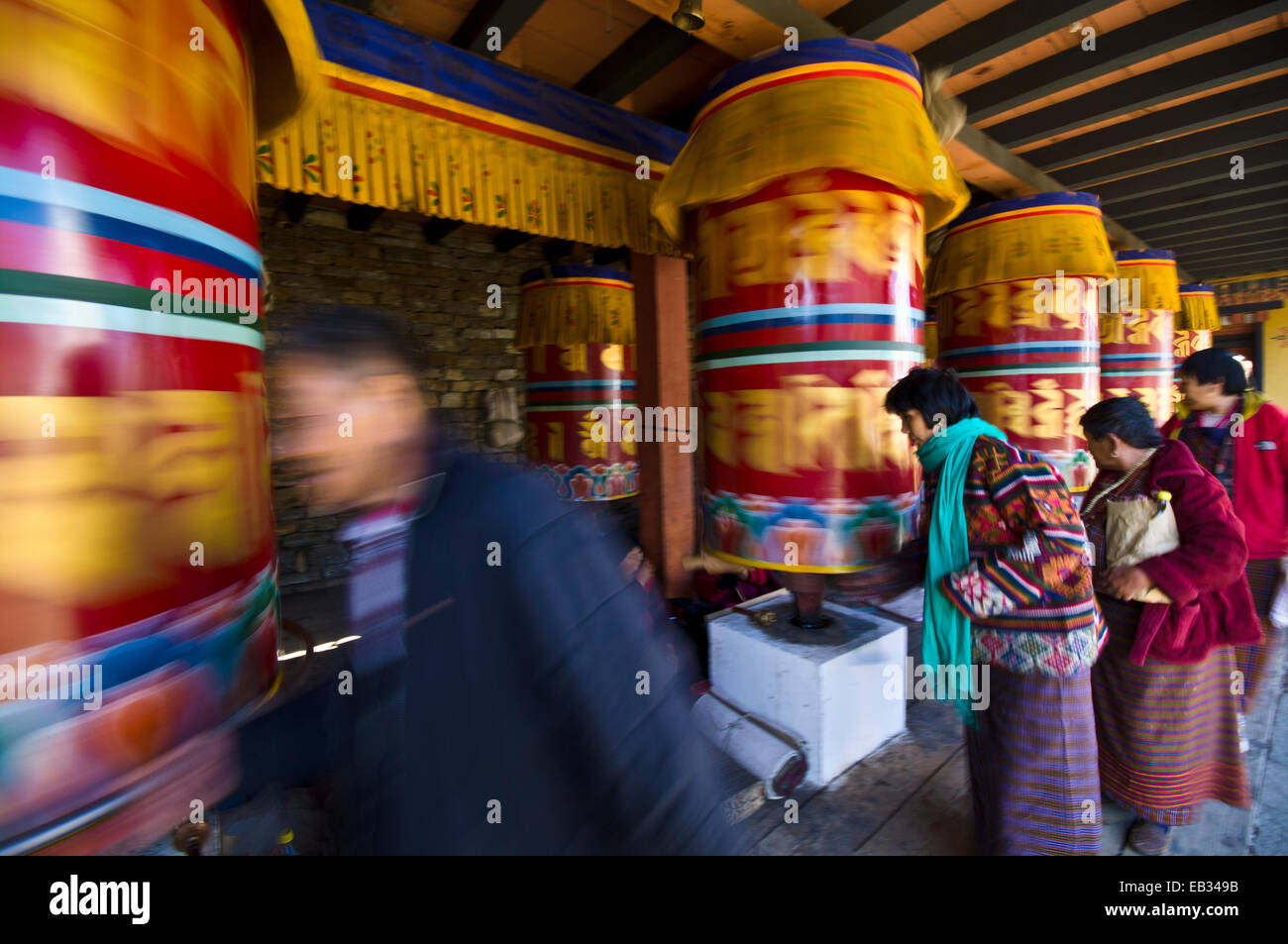 Buddhists march past colorful prayer wheels spinning them whilst making prayers and aspirations. Stock Photo