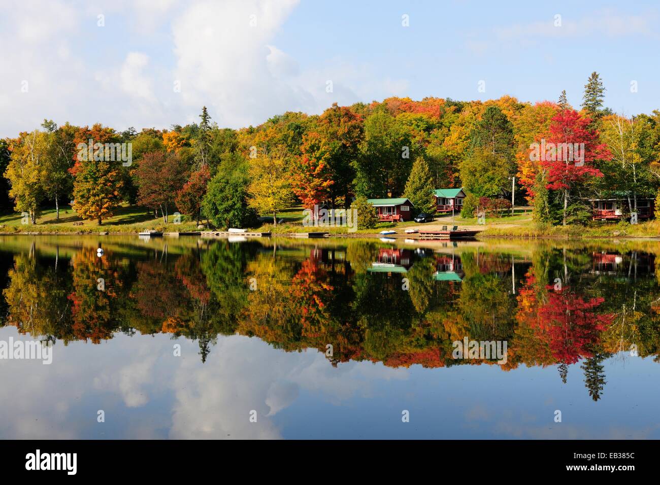 Forest in autumn colours and houses reflected in Galeairy Lake, typical lake and forest landscape of the Canadian Shield Stock Photo