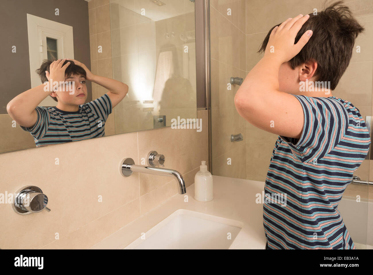 Young boy looking in the mirror in the bathroom Stock Photo