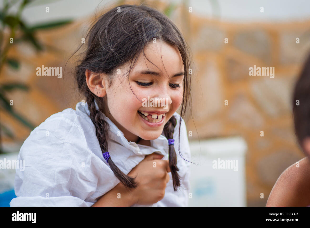 Little girl (6-7) with braids and white shirt laughing happily Stock Photo