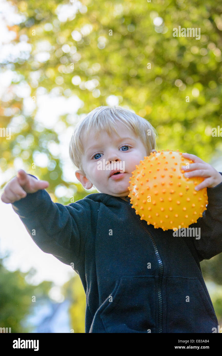 Boy in a park holding a ball and pointing Stock Photo