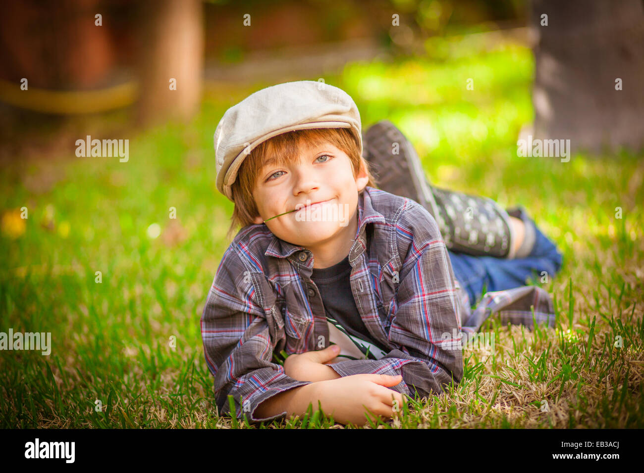 Boy lying on grass with blade of grass in mouth Stock Photo Alamy