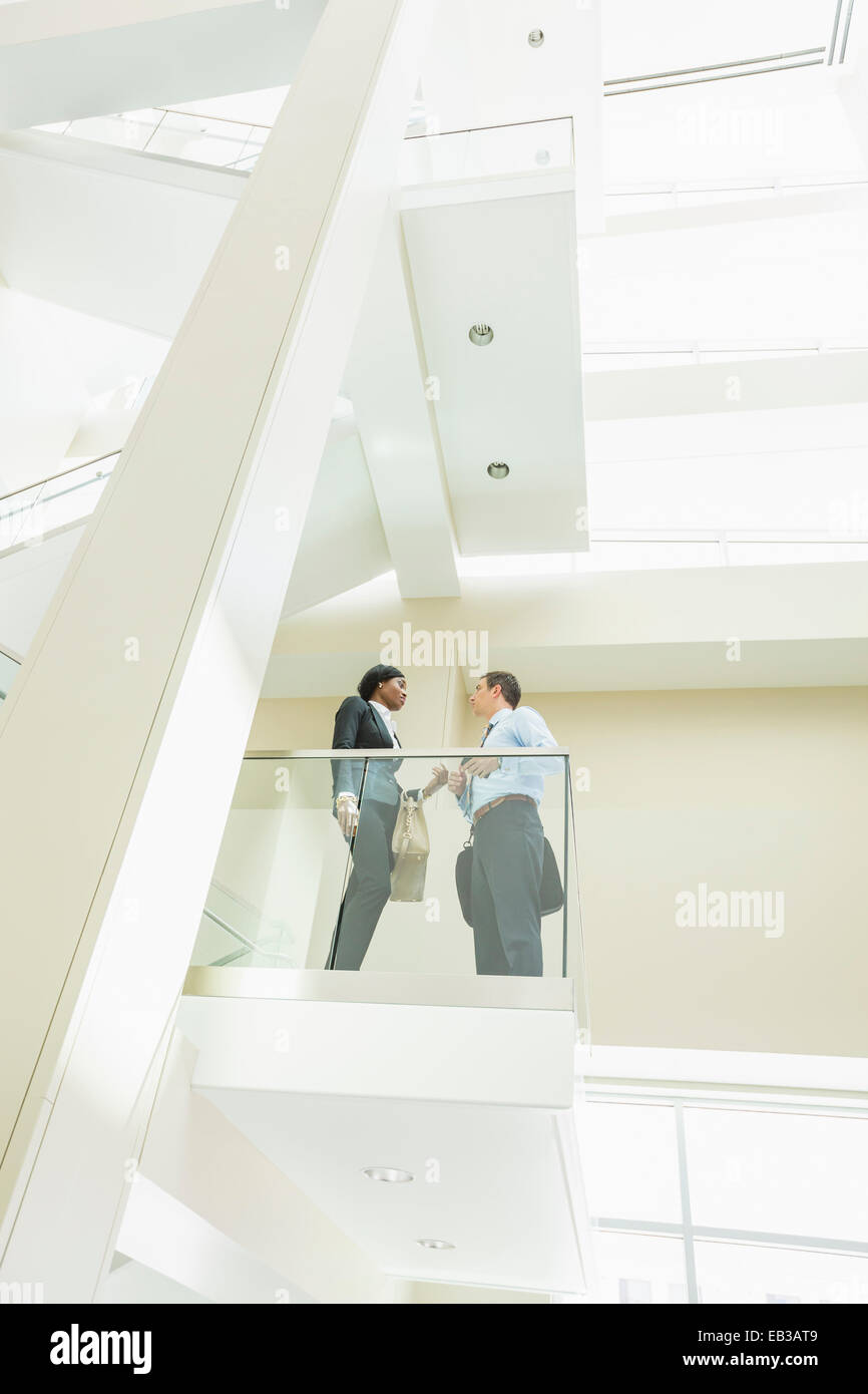 Low angle view of business people talking on office balcony Stock Photo
