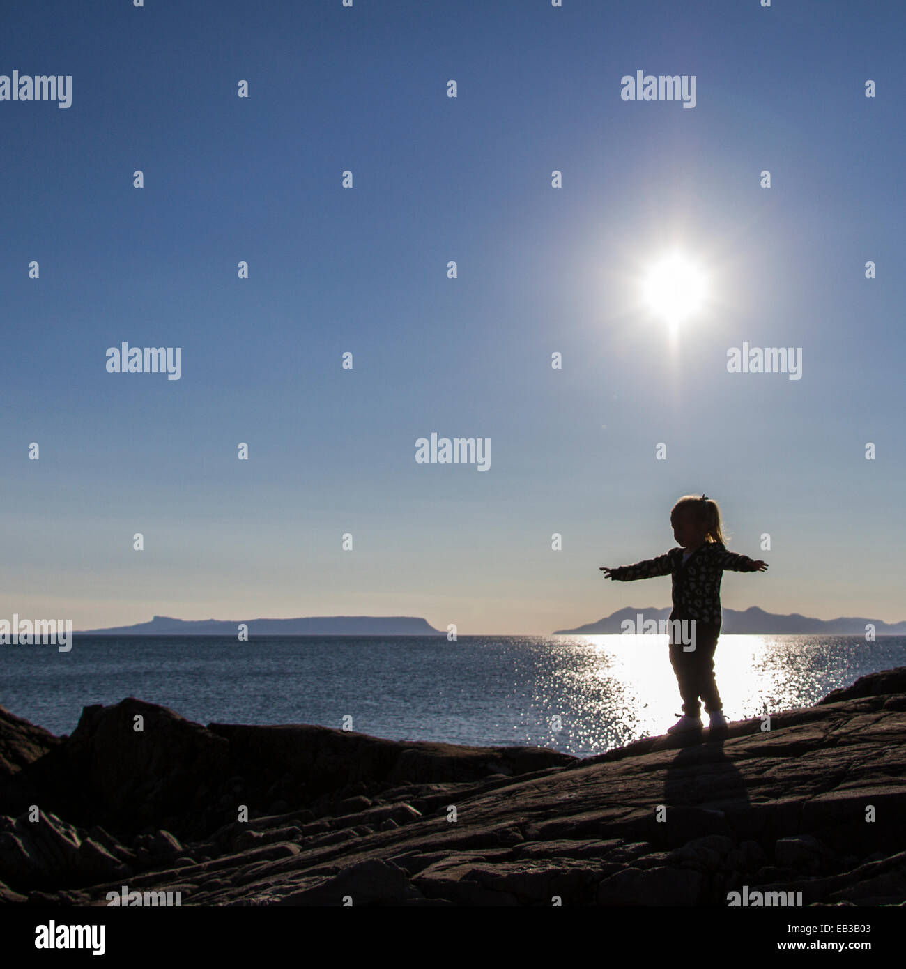 Girl standing on rocks with her arms outstretched, England, UK Stock Photo