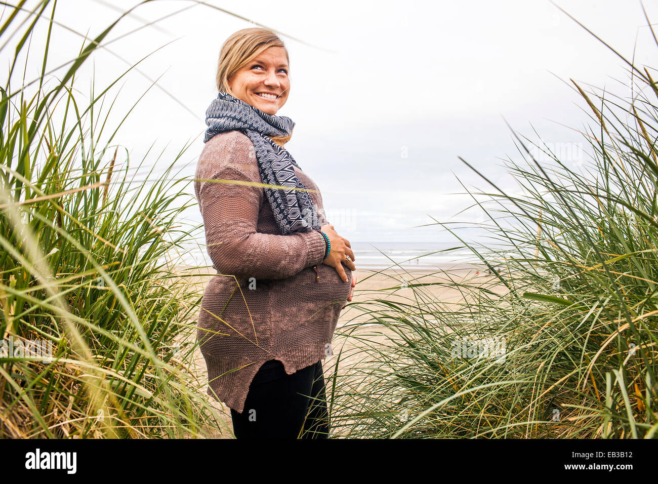 Caucasian pregnant woman holding her stomach on beach Stock Photo