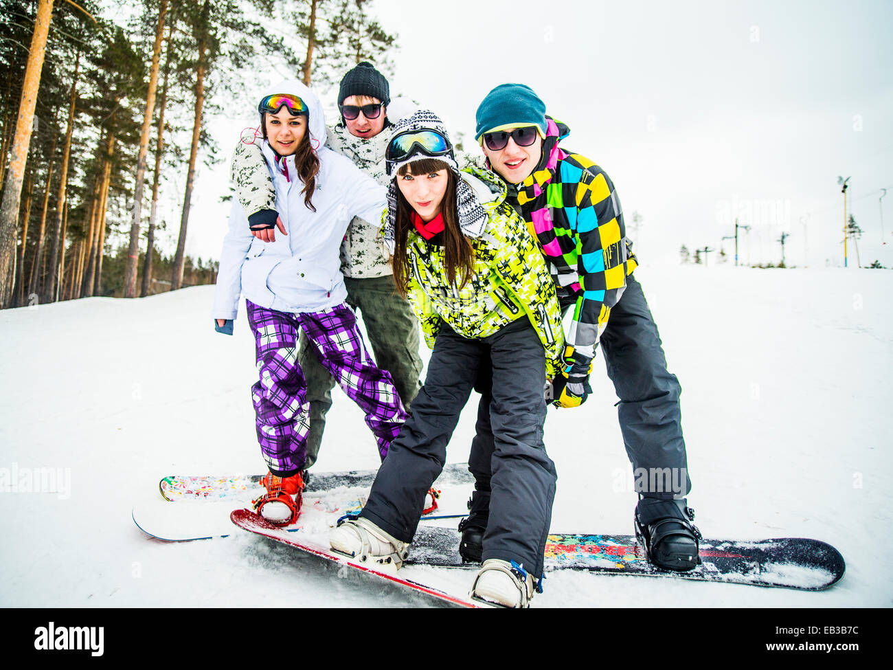 Caucasian couples snowboarding posing on snowy slope Stock Photo