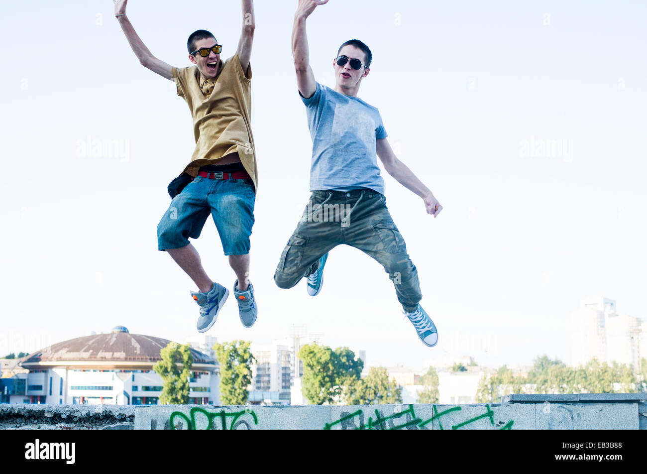 Caucasian men jumping for joy in city Stock Photo
