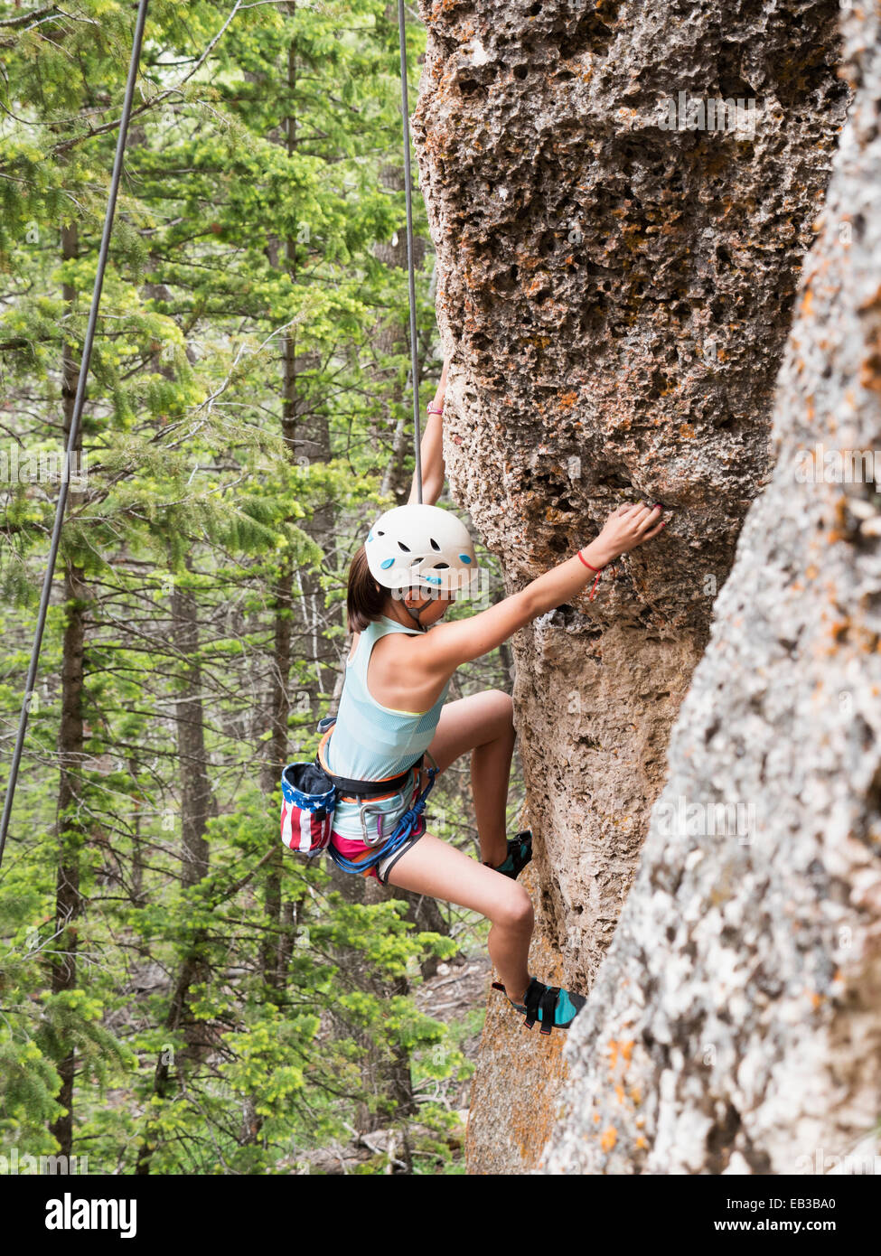 Mixed race girl climbing steep cliff Stock Photo