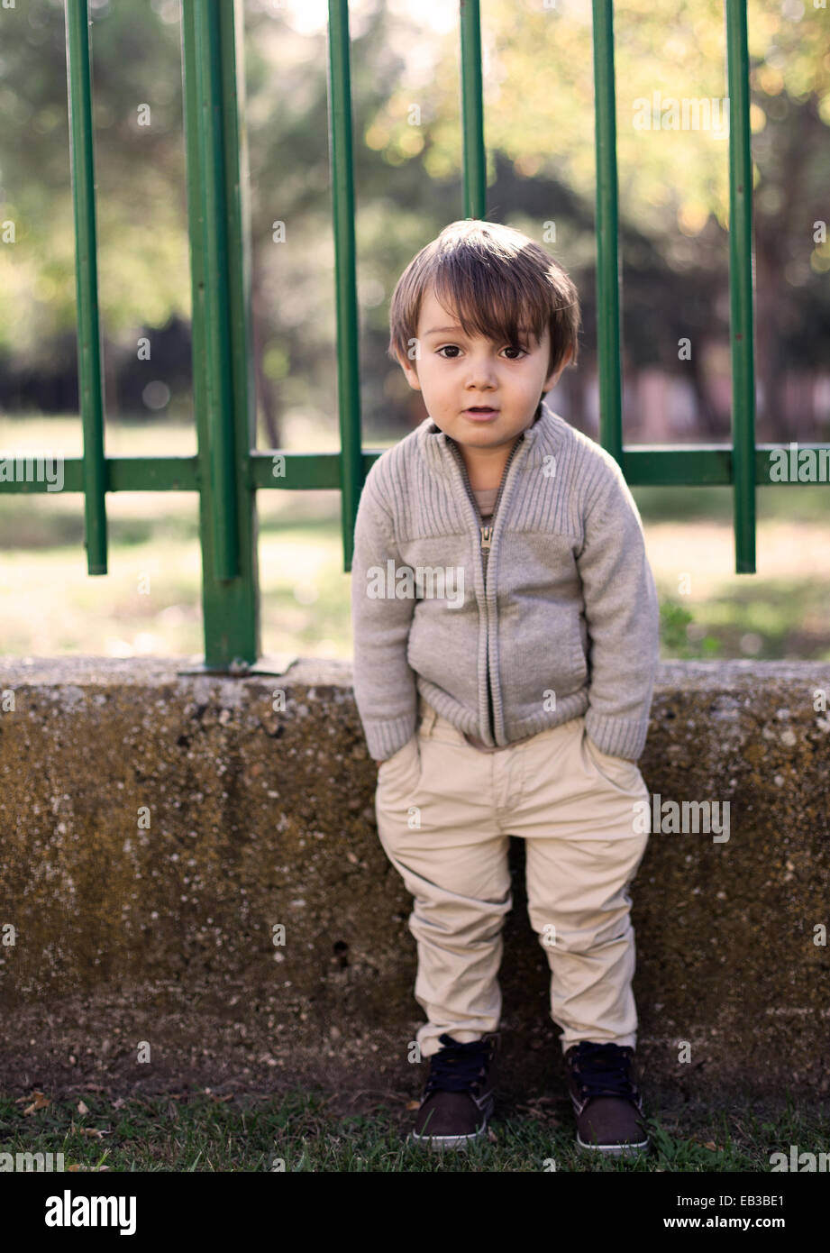 Boy standing by railings with his hands in his pockets Stock Photo