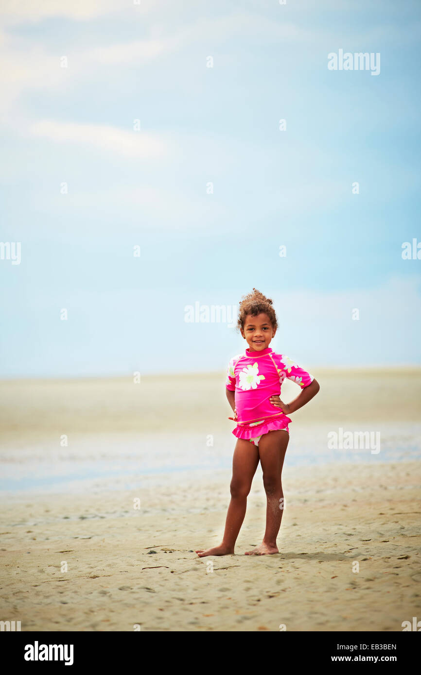 Mixed race girl standing on beach Stock Photo
