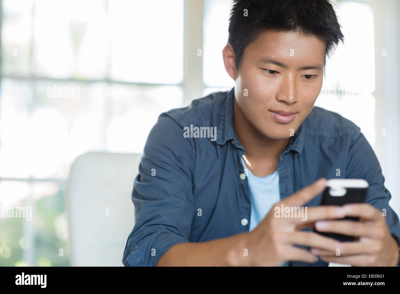 Korean man using cell phone indoors Stock Photo Alamy