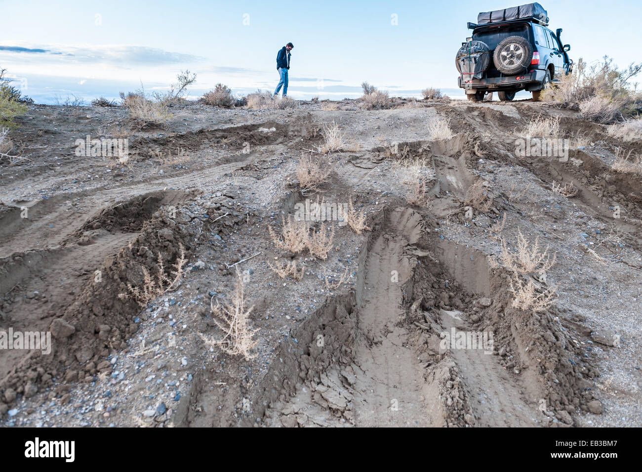 Man checking road conditions on muddy track, Black rock desert, Nevada
