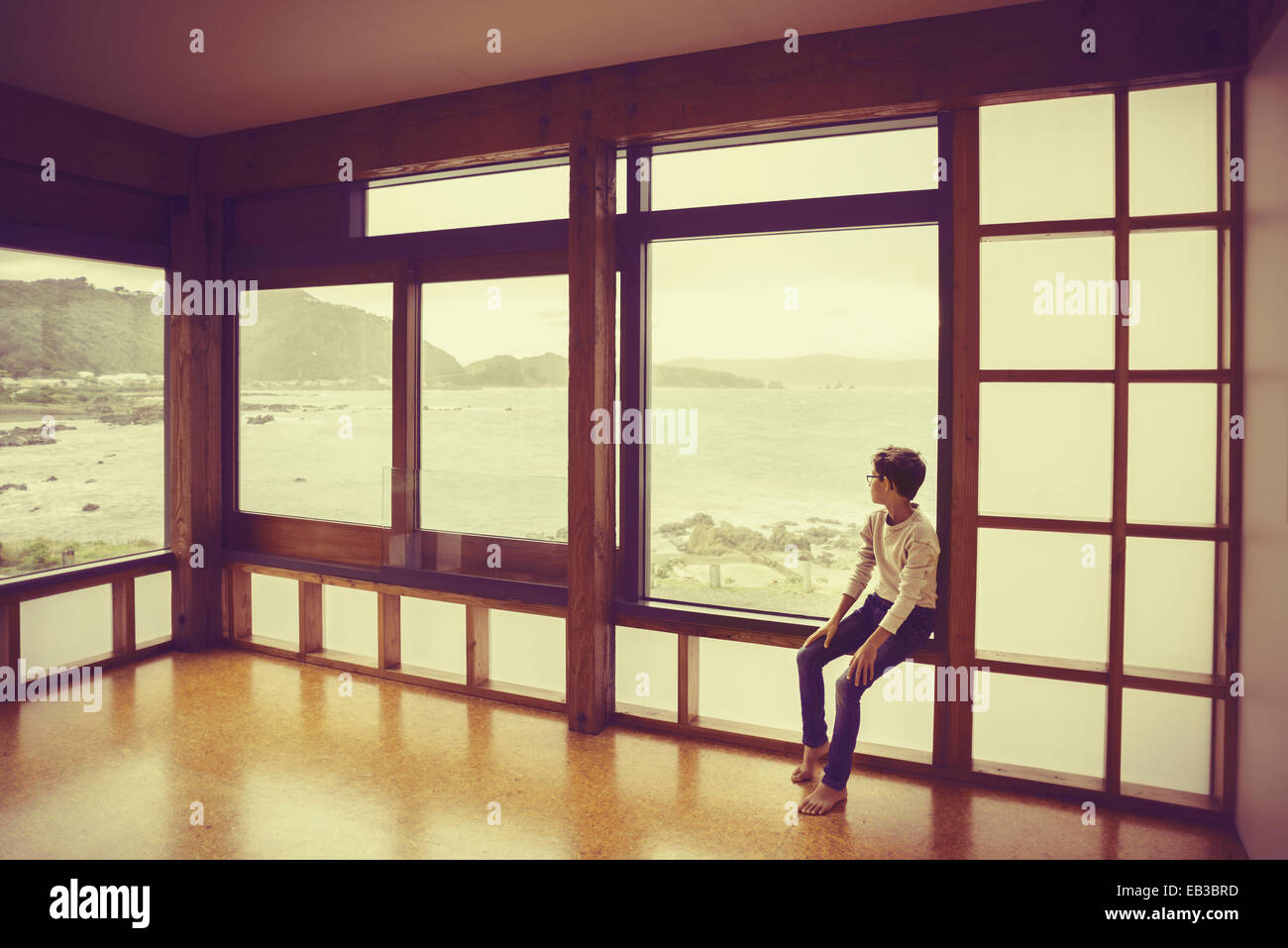 Mixed race boy looking out window Stock Photo