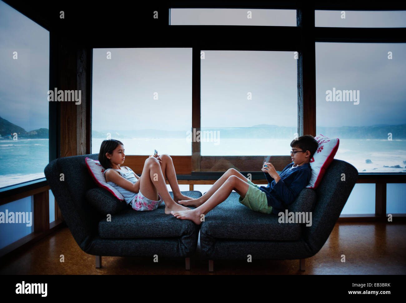 Mixed race children using cell phones in living room Stock Photo