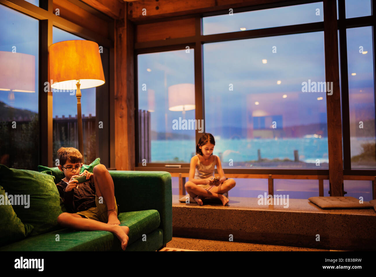 Mixed race children using cell phones in living room Stock Photo